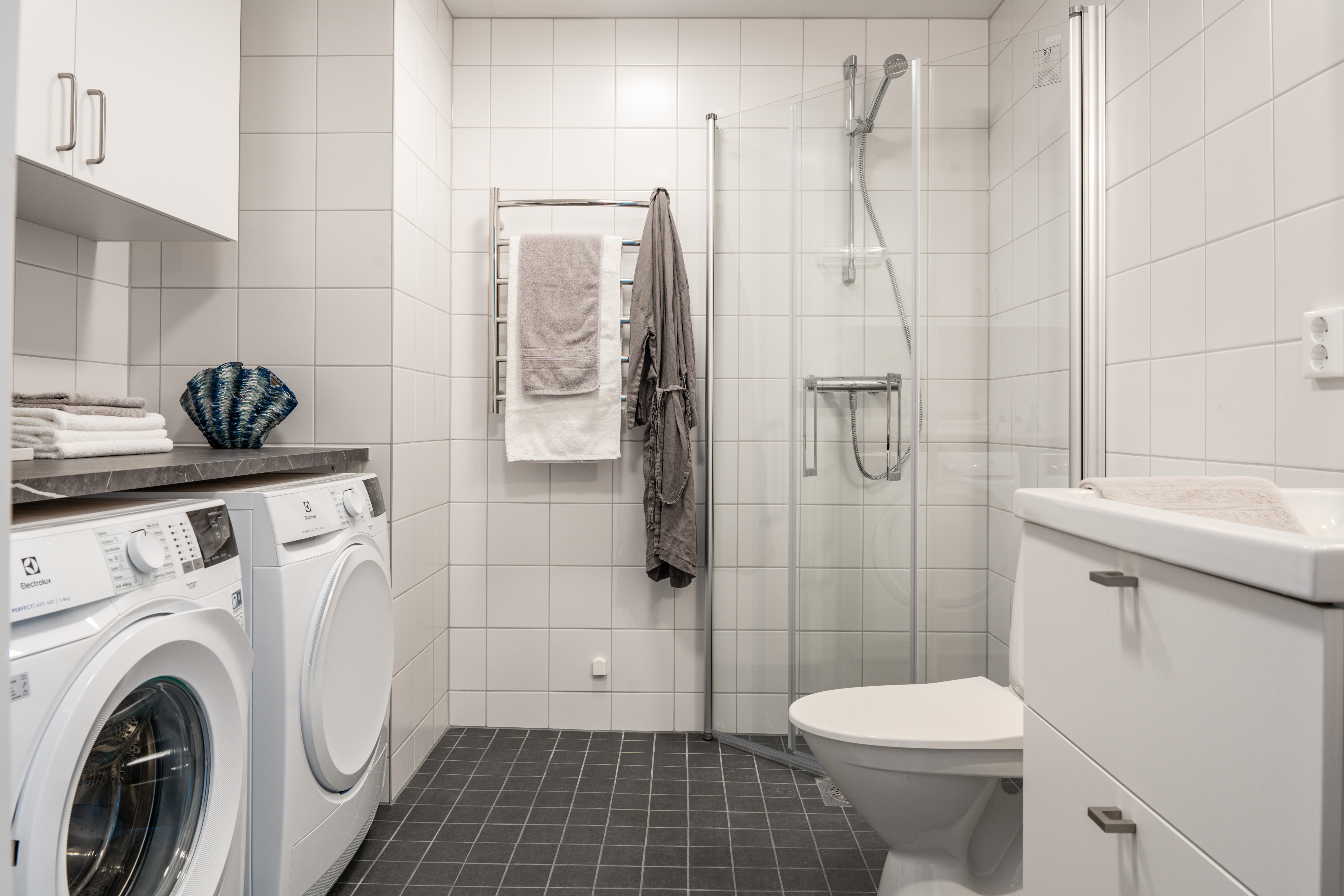 Bild på badrum med tvättmaskin, torktumlare och dusch