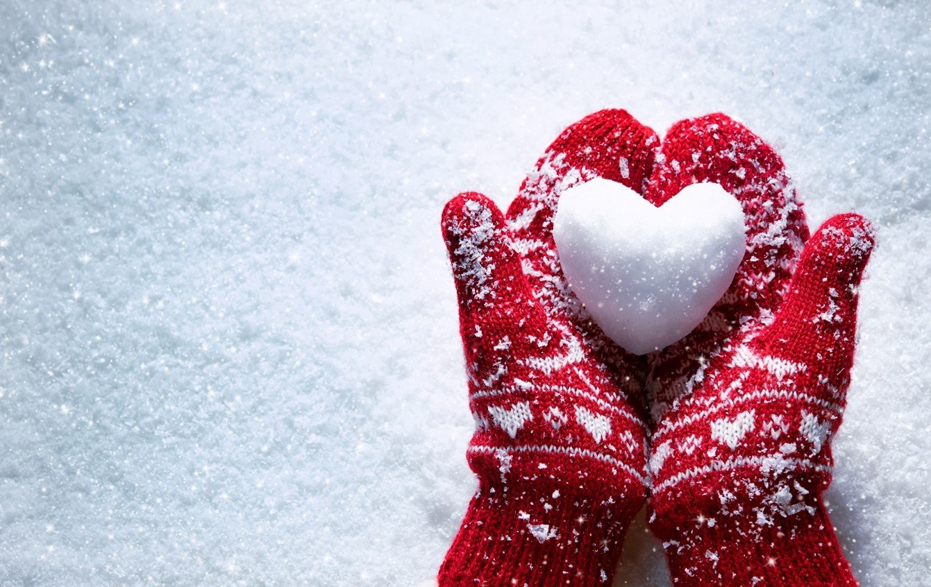 Snöboll format som ett hjärta i vantklädda händer