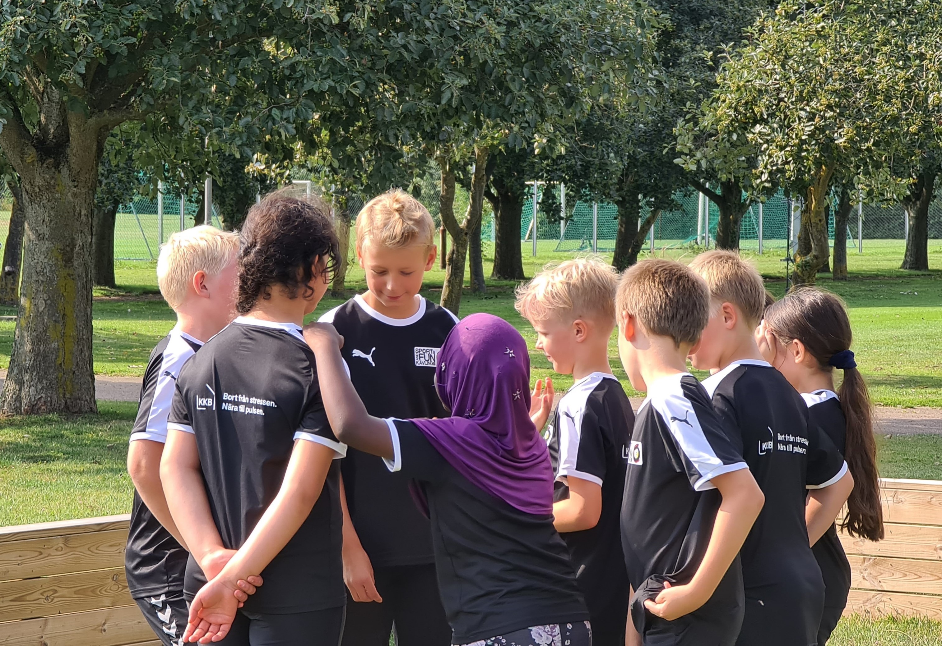 Barn som samlas i ring på fotbollsplan